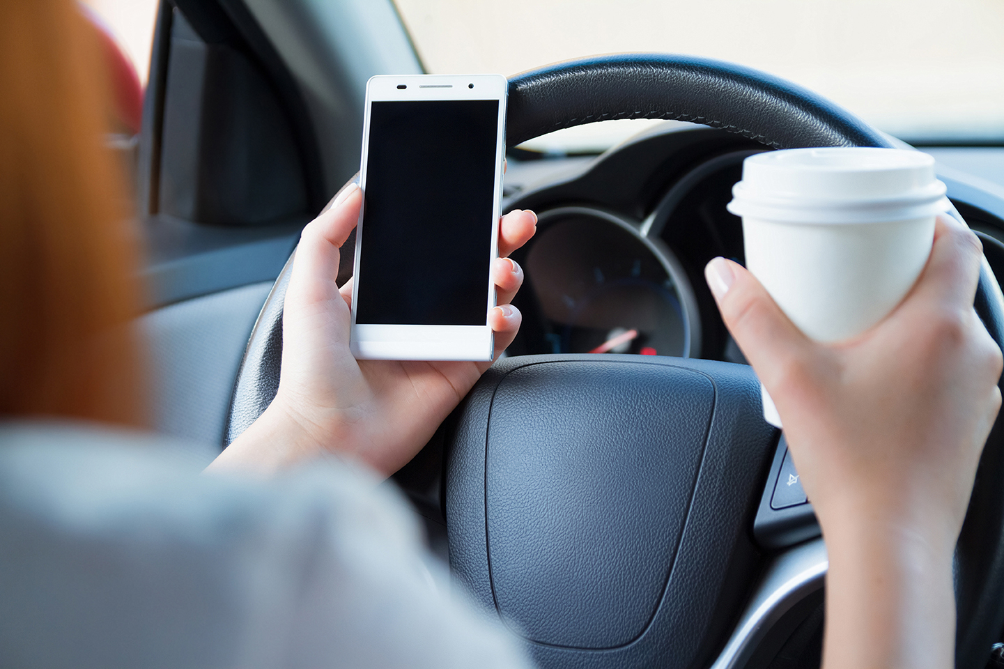 Car driver distracted by cell phone use.