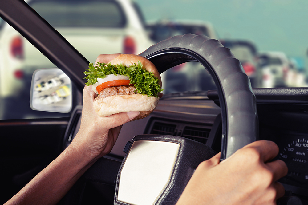 Car driver distracted by eating.